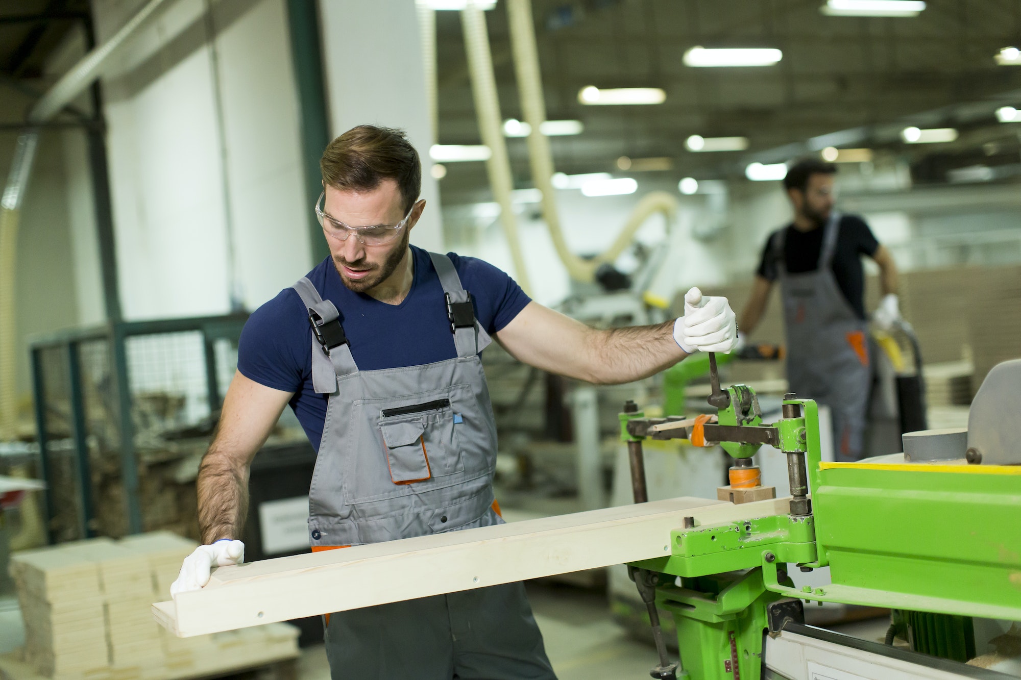 Young man works in a factory for the production of furniture